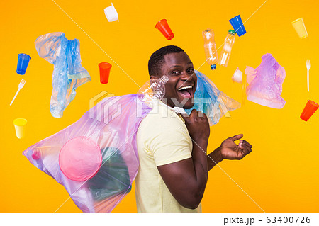 Problem of trash, plastic recycling, pollution and environmental concept - funny man carrying garbage bag on yellow background 63400726