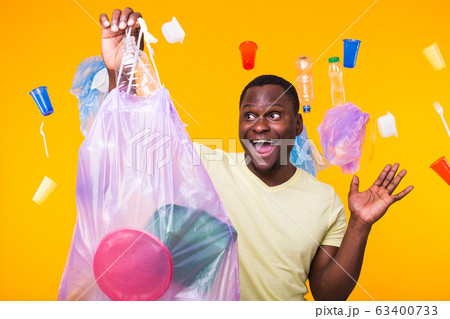 Problem of trash, plastic recycling, pollution and environmental concept - surprised man carrying garbage bag on yellow background 63400733