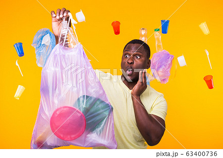 Problem of trash, plastic recycling, pollution and environmental concept - surprised man carrying garbage bag on yellow background 63400736