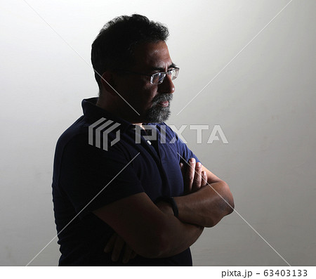 A smiling Indian man with a goatee in a studio against a white background. Wearing spectacles and looking away from camera to the right A smiling Indian man with a goatee in a studio against a white background. Wearing spectacles and looking away from camera to the right 63403133