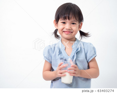 Asian little cute girl 4 years old holding and drinking milk from glasses over white background. Milks is essential and nutrition for the child's body. Asian little cute girl 4 years old holding and drinking milk from glasses over white background. Milks is essential and nutrition for the child's body. 63403274