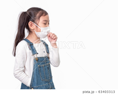 Asian little cute girl 6 years old wearing a hygienic mask to protective spread the disease and coughing on white background. Prevention of spreading the virus, cold flu or pollution. Asian little cute girl 6 years old wearing a hygienic mask to protective spread the disease and coughing on white background. Prevention of spreading the virus, cold flu or pollution. 63403313