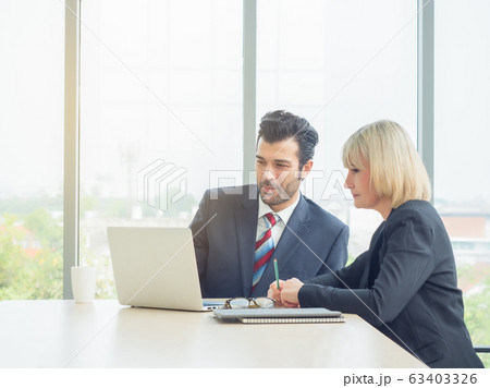 Business man and woman talking together and looking laptop on table at meeting room. Teamwork, partnership concept 63403326