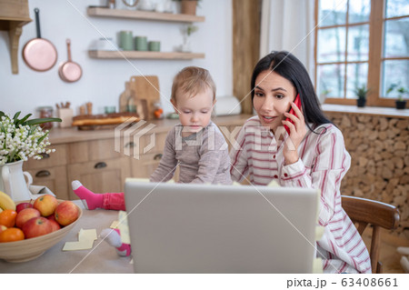 Mom sitting with daugher at laptop, talking on phone Mom sitting with daugher at laptop, talking on phone 63408661