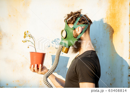 Man with gas mask and flowerpot 63408814