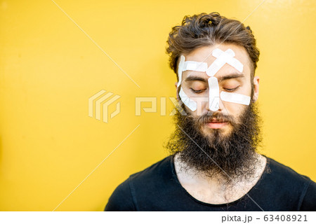 Man with medical patches on his face 63408921