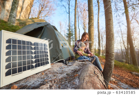 Close up solar battery in campsite on sunny autumn day against the background of young family 63410585