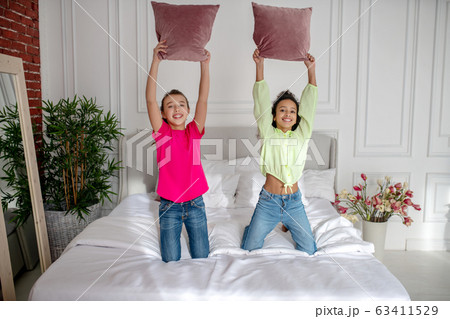 Two pretty girls holding pillows and looking enjoyed Two pretty girls holding pillows and looking enjoyed 63411529