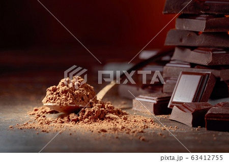 Broken chocolate pieces and cocoa powder . Broken chocolate pieces and cocoa powder . 63412755