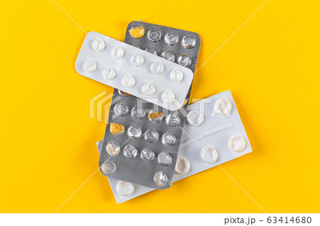 A pile Used blister packs of pills on yellow background 63414680