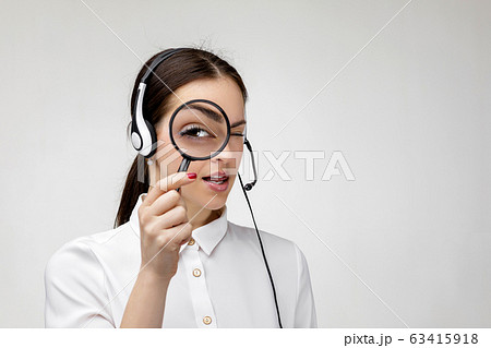woman consultant of call center in headphones holding magnifying glass 63415918