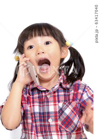 スマホを耳に当て驚き顔の幼い女の子。喜び、スマートフォン、驚きイメージ 63417040