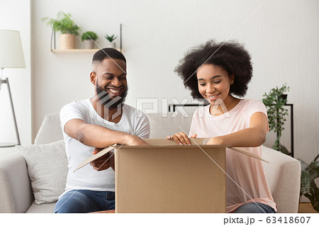 Smiling man and woman open a box from online store Smiling man and woman open a box from online store 63418607