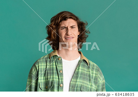 Millennial guy with disgusted expression on turquoise background Millennial guy with disgusted expression on turquoise background 63418635