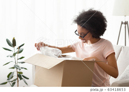 Girl in glasses unpacks purchase and considers it Girl in glasses unpacks purchase and considers it 63418653