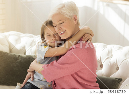 Aged woman with her grandchild embracing each other in light room Aged woman with her grandchild embracing each other in light room 63418739