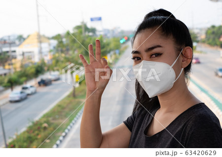 Woman putting on a respirator N95 mask to protect from airborne respiratory diseases as the flu Woman putting on a respirator N95 mask to protect from airborne respiratory diseases as the flu 63420629