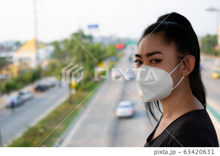 Woman putting on a respirator N95 mask to protect from airborne respiratory diseases as the flu Woman putting on a respirator N95 mask to protect from airborne respiratory diseases as the flu 63420631
