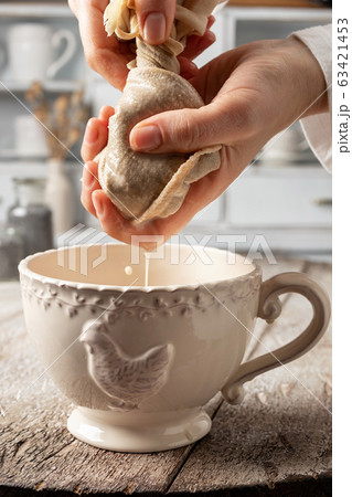 Straining poppy seed milk through a milk bag 63421453