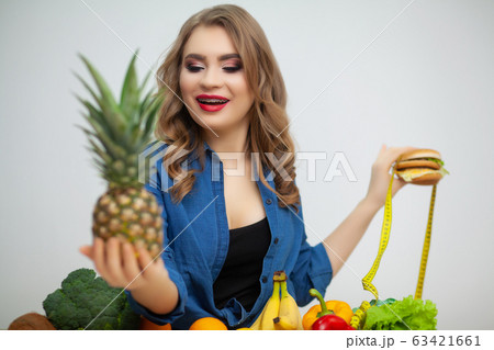 Concept of healthy eating, burger with yellow tape measure and ripe pineapple. Concept of healthy eating, burger with yellow tape measure and ripe pineapple. 63421661