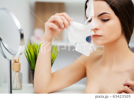 Pretty young woman with facial mask in bathroom 63423505