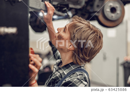 Caucasian female worker using a hydraulic jack Caucasian female worker using a hydraulic jack 63425086