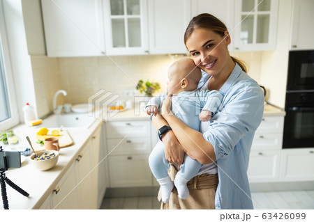 Happy young mother playing with her baby in the kitchen Happy young mother playing with her baby in the kitchen 63426099