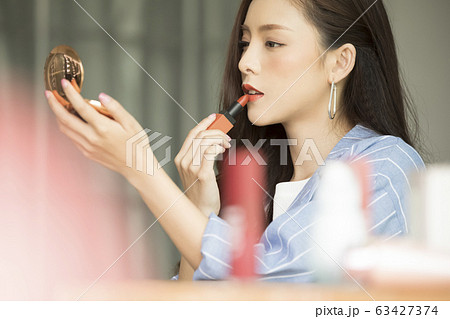 メイクアップをするジャケットを着た若い女性 63427374