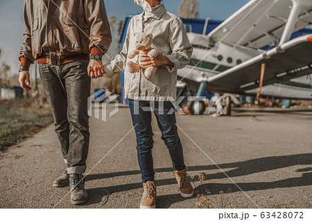 Little kid holding toy and walking with father outdoors 63428072