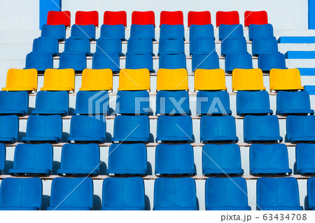 Empty old blue seats in the blue,yellow and red in stadium. Empty old blue seats in the blue,yellow and red in stadium. 63434708