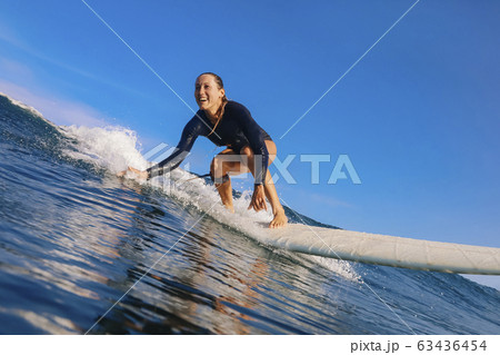 Female surfer on a blue wave 63436454