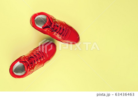Red sneakers on pastel yellow background. Concept of sport and healthy lifestyle Red sneakers on pastel yellow background. Concept of sport and healthy lifestyle 63436463