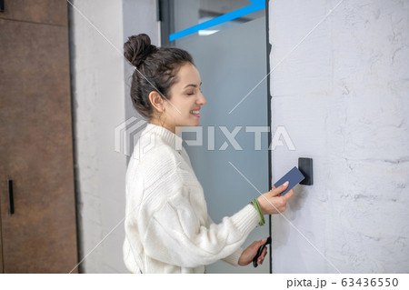 Young woman holding access card to unclock the door, smiling Young woman holding access card to unclock the door, smiling 63436550