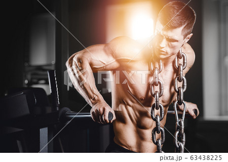 Bodybuilder pumping up chest muscles push-ups bars 63438225