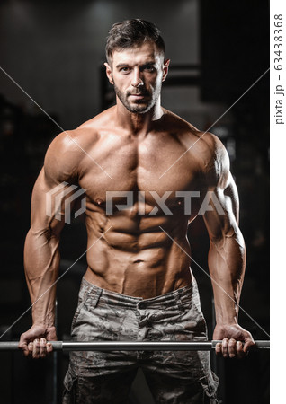 Bodybuilder strong man pumping up biceps muscles Bodybuilder strong man pumping up biceps muscles 63438368