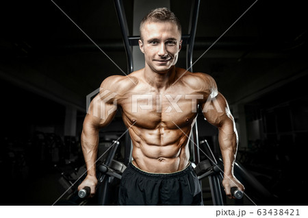Bodybuilder strong man pumping up abs muscles 63438421