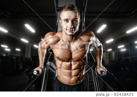 Bodybuilder pumping up chest muscles push-ups bars Bodybuilder pumping up chest muscles push-ups bars 63438425
