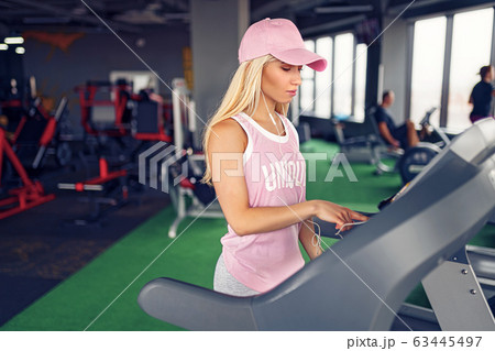 Side view of sporty blonde woman exercising on treadmill in gym Side view of sporty blonde woman exercising on treadmill in gym 63445497
