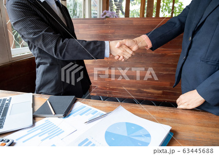 Two business women shaking hands after analysis the chart, set targets for new management success Two business women shaking hands after analysis the chart, set targets for new management success 63445688