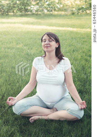 Young pregnant woman meditating while sitting in Young pregnant woman meditating while sitting in 63446560