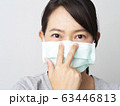 Asian woman was cold and sick, she wear green mask to prevent the virus covid. How to wear and pull mask from face. Covid 19 spread from Chinese people in Wuhan city. Close up face and eyes. 63446813