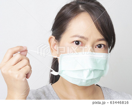 Asian woman was cold and sick, she wear green mask to prevent the virus covid. How to wear and pull mask from face. Covid 19 spread from Chinese people in Wuhan city. Close up face and eyes. 63446816
