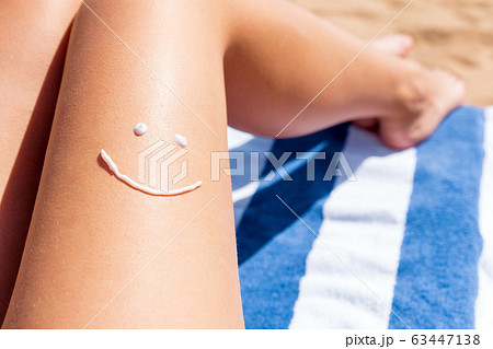 Smiling face is drawn on smooth tanned female leg 63447138