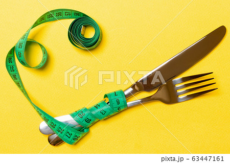 Crossed fork and knife are wrapped in measuring Crossed fork and knife are wrapped in measuring 63447161