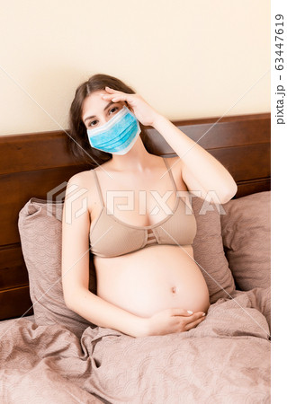 Young pregnant woman in protective medical mask  63447619