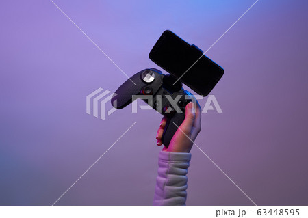 Female hands with a game joystick with smartphone on violet background. 63448595