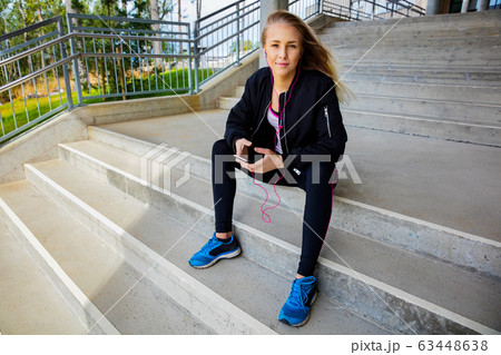 Young Woman In Sportswear Listening Music On Smartphone 63448638