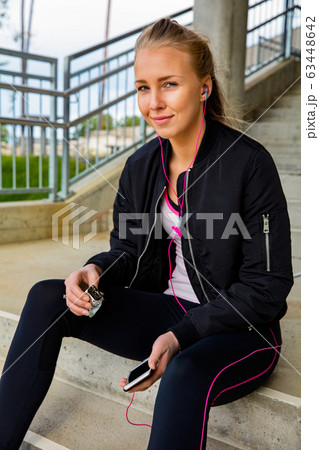 Sporty Woman Holding Protein Bar And Smart Phone On Steps 63448642