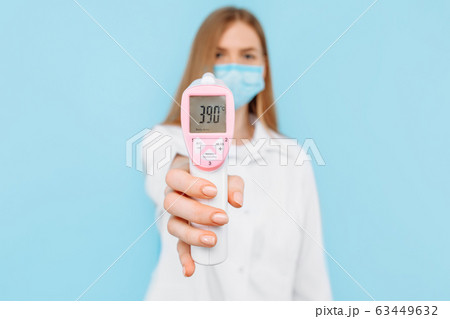 A female doctor in a protective mask measures the 63449632