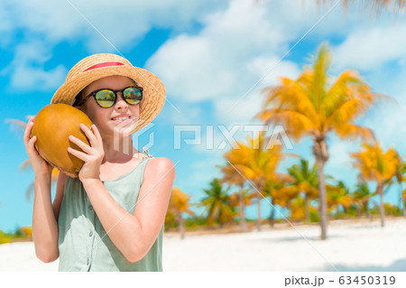 Little adorable girl with big coconut on the beach 63450319